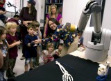 ASU assistant engineering professor Veronica Santos (at right) instructs preschool students how to use a sensor glove to control the fingers on a robot hand at the Biomechatronics Lab. (Photo: Jessica Slater/ASU)