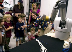 ASU assistant engineering professor Veronica Santos (at right) instructs preschool students how to use a sensor glove to control the fingers on a robot hand at the Biomechatronics Lab. (Photo: Jessica Slater/ASU)