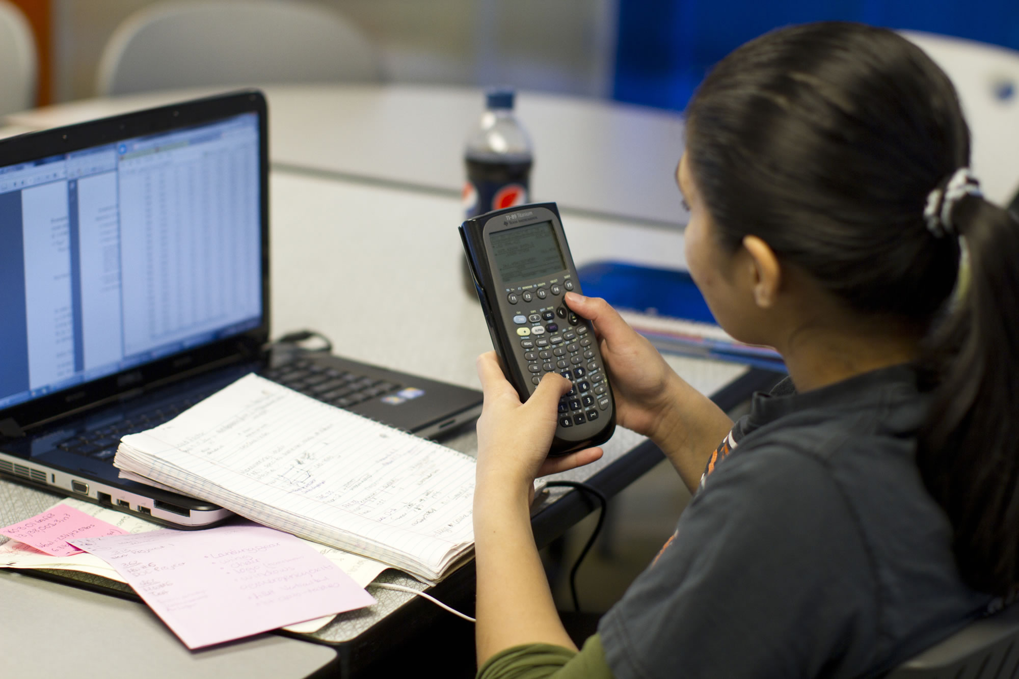 Engineering student working at her laptop holding a calculator