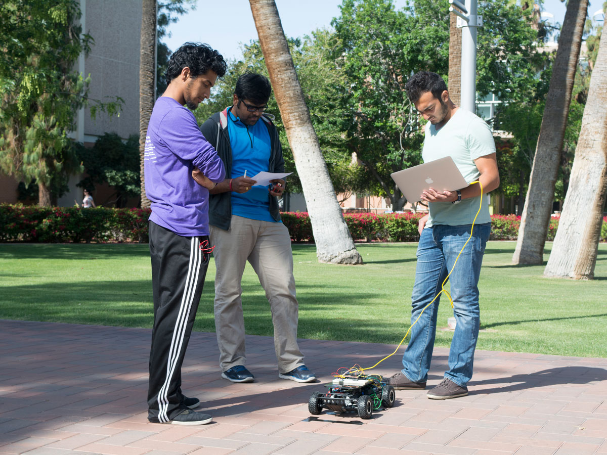 Syed, a teaching assistant and Ahmed do some last minute work on their car's code before a demonstration on April 15, 2016.