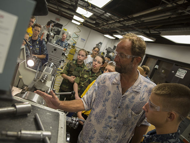 Neil O'Leary, a prototype machinist, shows cadets with the U.S. Naval Sea Cadet Corps the basic functions of a lathe in the Student Machine Shop, located in the basement of the Bateman Science Building F wing on August 20, 2016. The cadets were welcomed by Alicia and Jennifer Flores, Navy veterans and former cadets themselves, both enrolled in the Fulton Schools in the aerospace and electrical engineering programs, respectively. The cadets visited the Tempe campus to learn about educational and career pathways in engineering as well as tour different labs and facilities used by engineering students and faculty. The USNSCC is a federally-chartered nonprofit development program that educates young people about the benefits of serving in the armed forces, particularly the G.I. Bill. Even the cadets who do not serve still benefit from the discipline and values gained in the program. Photographer: Pete Zrioka