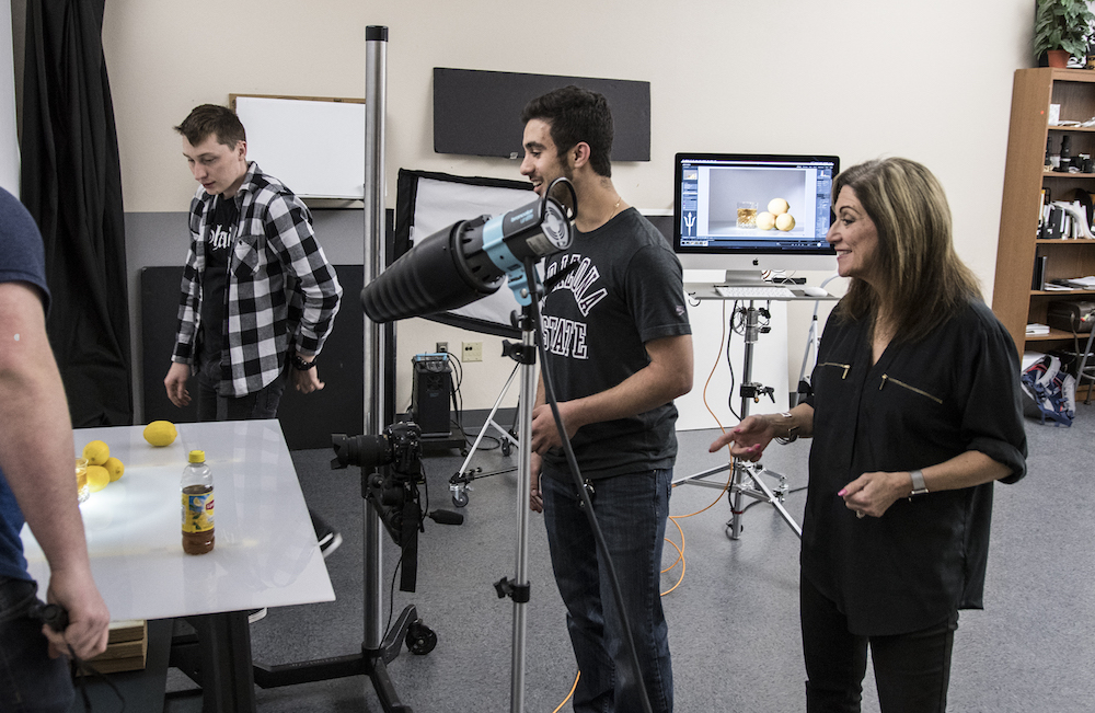 Penny Ann Dolin (right) teaching students in the Graphic Information Technology photo studio. Photographer: Kahn Van Toor/ASU