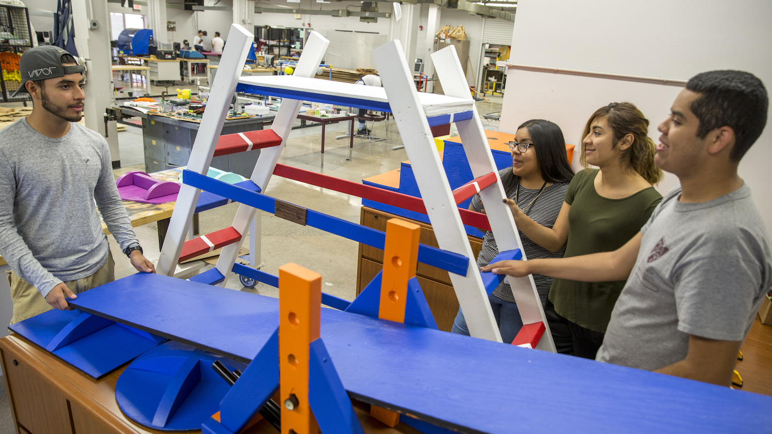 Photo of four students standing to ladder-like structure