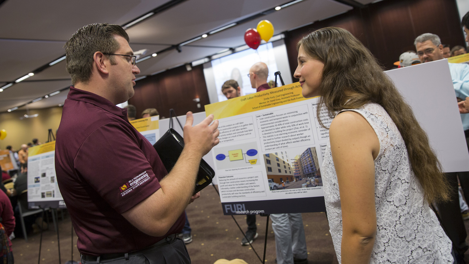 Photo of female student talking with a man in front of a poster with a caption of "Sharing your research and ideas at the FURI Symposium are part of the experience for undergraduate researchers like Emily Ford (right). Photographer: Jessica Hochreiter/ASU."