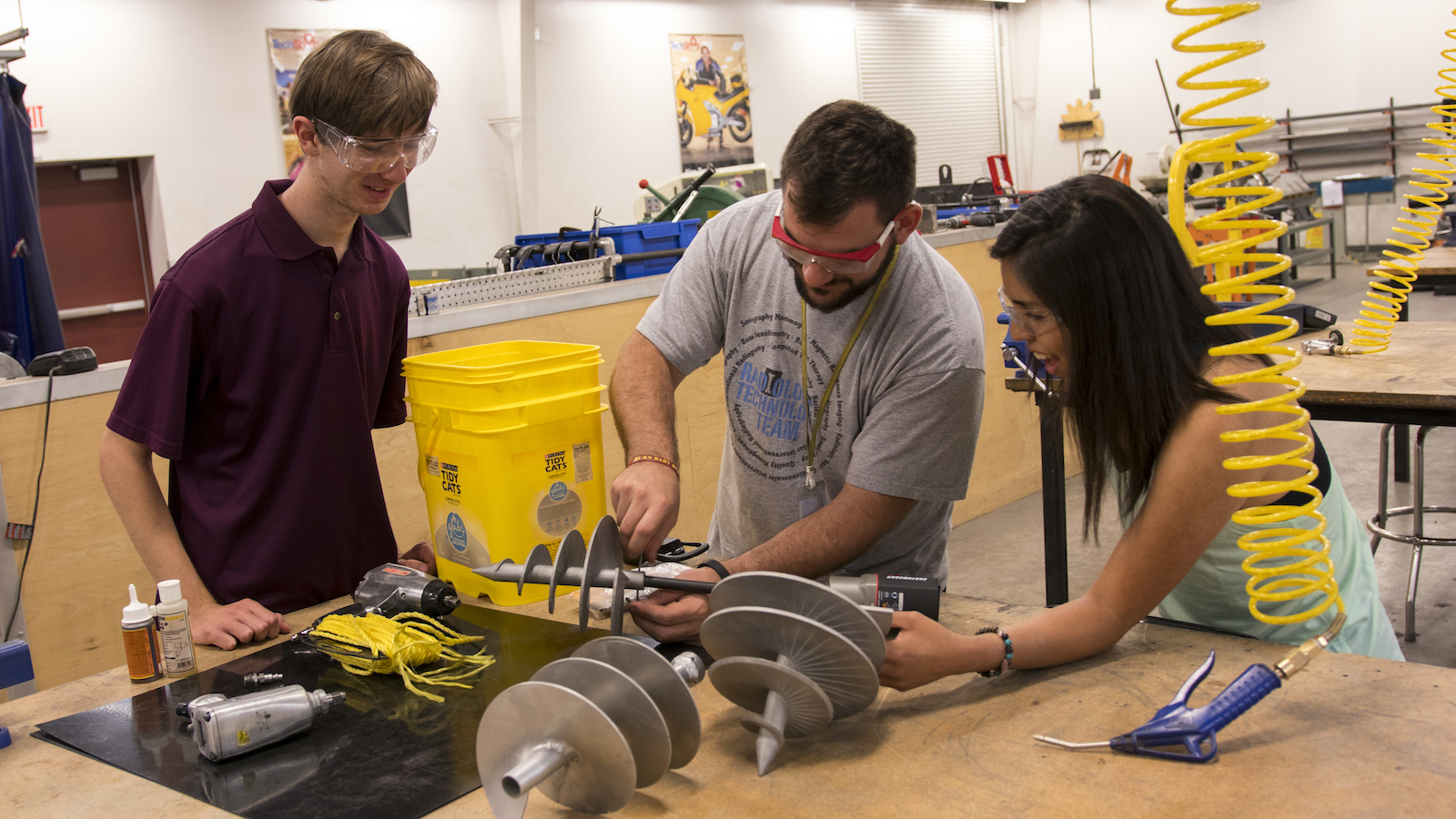 Photo of three students attaching an auger to a drill with a caption of "The Next Level Devils preparing to test their conical tapered anchor prior to heading to NASA’s Neutral Buoyancy Laboratory near the Johnson Space Center in Houston, Texas. Photographer: Marco-Alexis Chaira/ASU"
