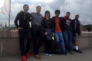 A group of young people crowd together for a photograph. In the background, the tell-tale spires of Moscow's classic architecture are visible. The caption reads: The ASU VisionHack team pauses for a group photo while out sightseeing in Moscow. Photo courtesy of Jared Schoepf