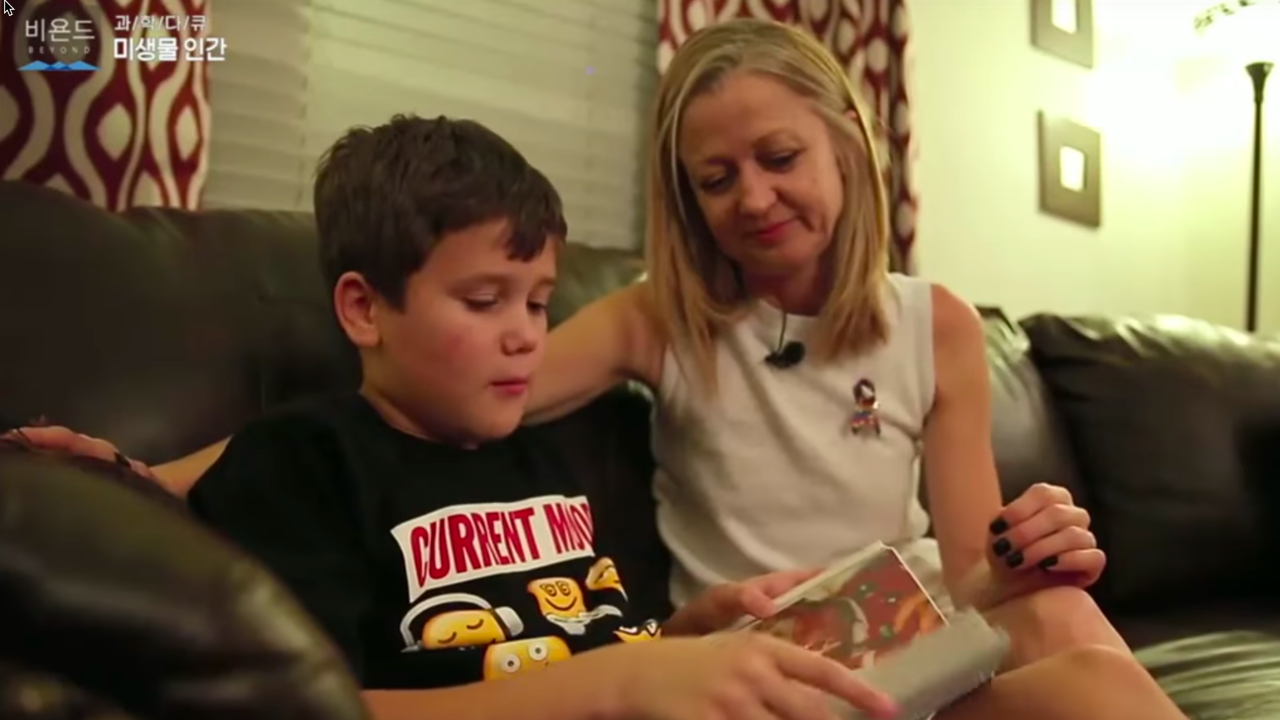 Photo of a mother and son sitting on a couch. Caption: The Korean documentary “Microbiome Human” includes an extensive segment that chronicles the case of a young boy with autism who had struggled with severe diarrhea from infancy. He received microbiota transplant therapy as part of a clinical trial led by ASU researchers. After treatment, the boy experienced a dramatic drop in symptoms of gastrointestinal disorder and a reduction of autism symptoms. Video image from the documentary “Microbiome Human.”