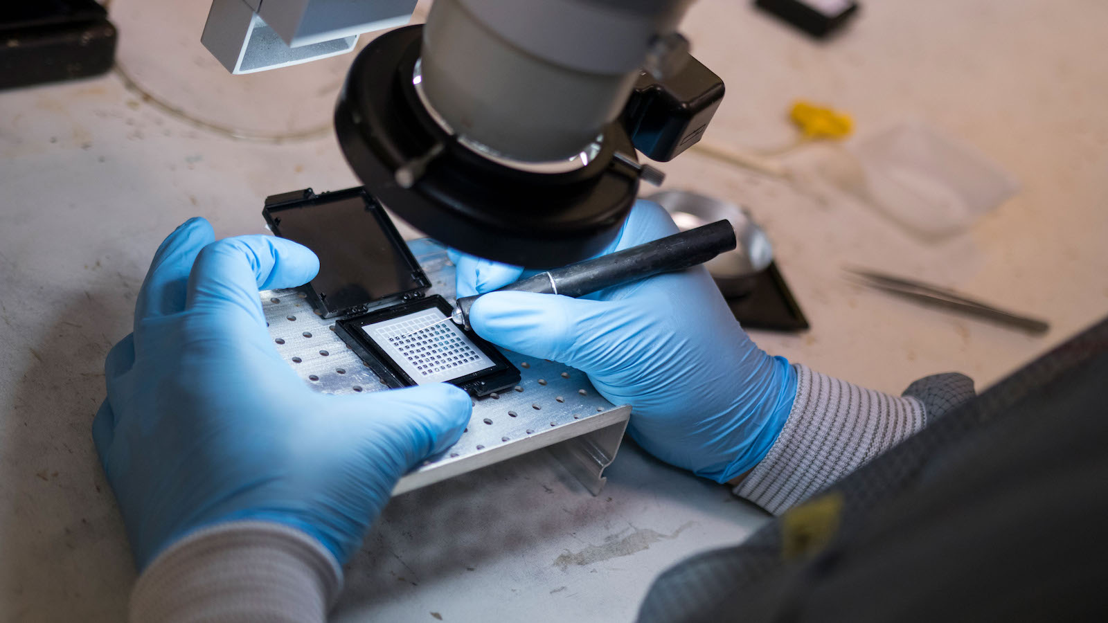 A close up of a pair of hands, one holding a pen-like tool and the other a small device. Caption: Laser Components DG’s photodetector manufacturing, assembly and testing involve performing highly precise, intricate and meticulously controlled procedures on small, delicate components and devices. Equally complex research and development operations are done by two of the company’s employees who work at ASU’s NanoFab facility. Photographer: Marco-Alexis Chaira/ASU