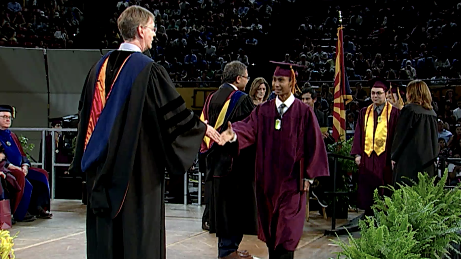 John Cava walking across the stage at Convocation.