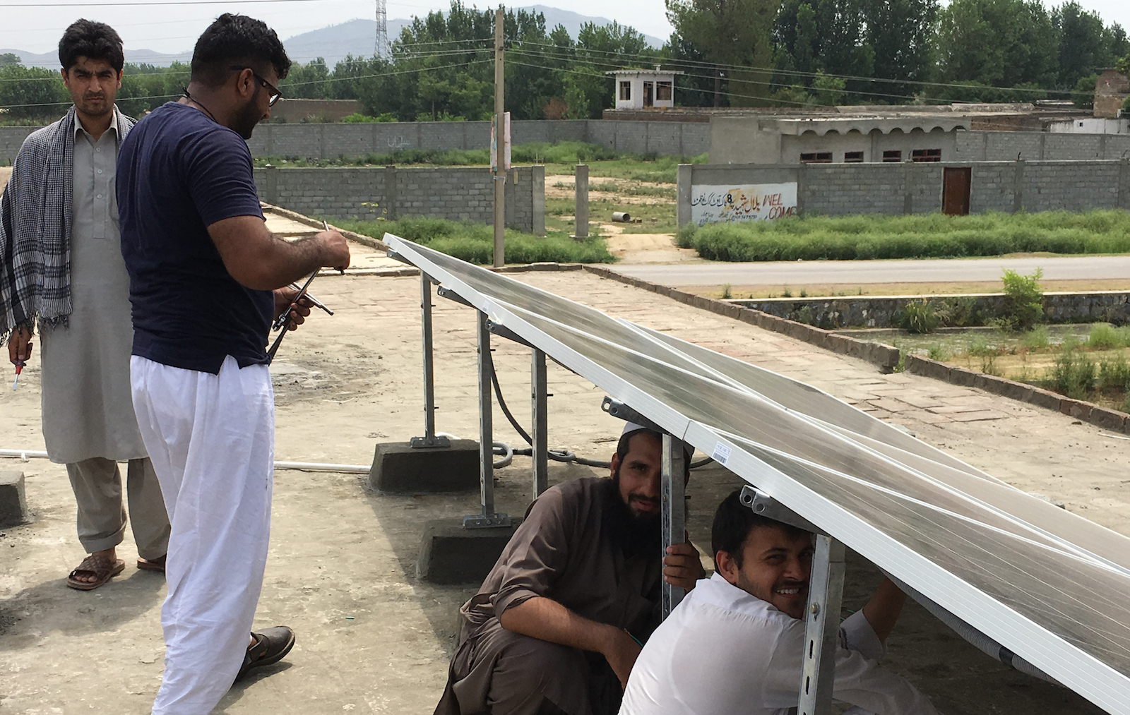 Four men working outdoors on solar panels in Pakistan