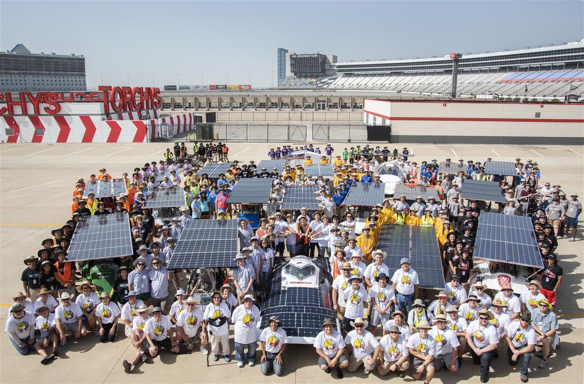 photo of solar powered cars with students all around them