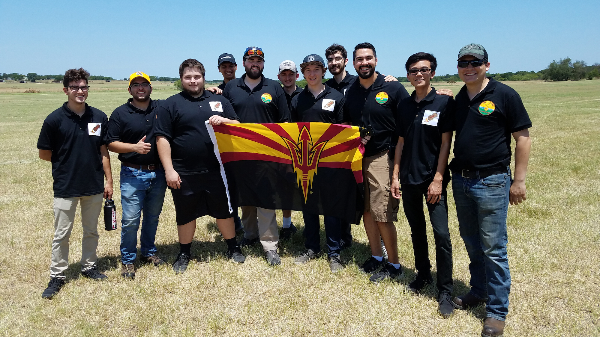 11 people standing in a field holding a flag