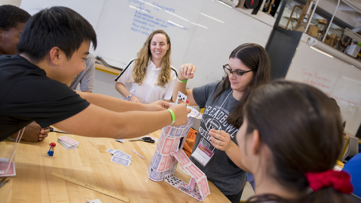 students building a tower made of playing cards