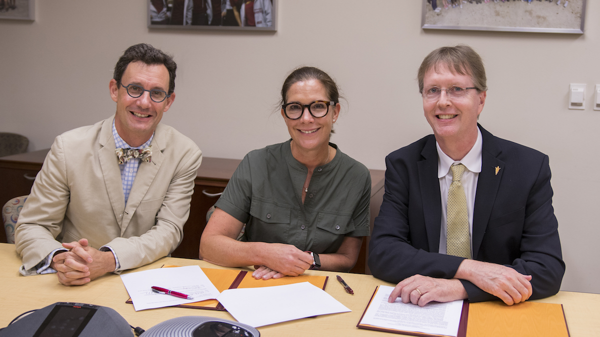 three people sitting at a long table