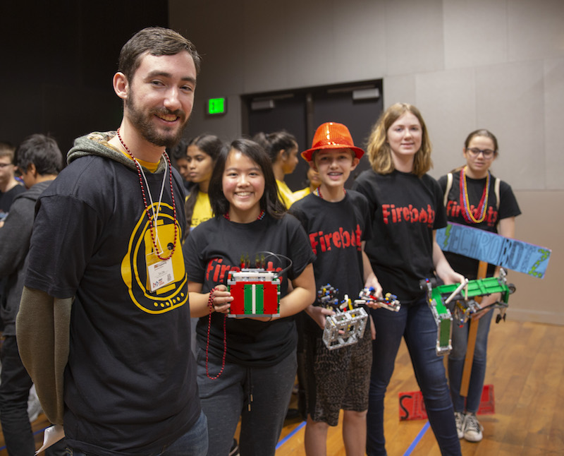 five people standing with four holding objects