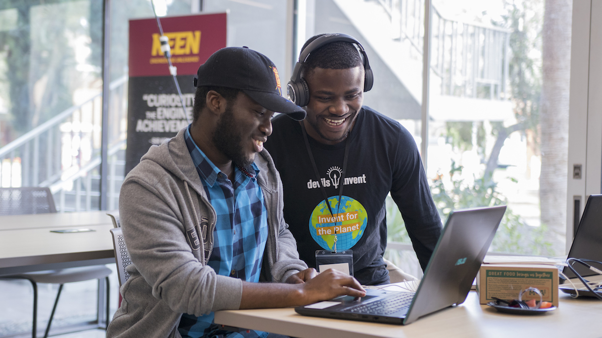 two men looking at a laptop