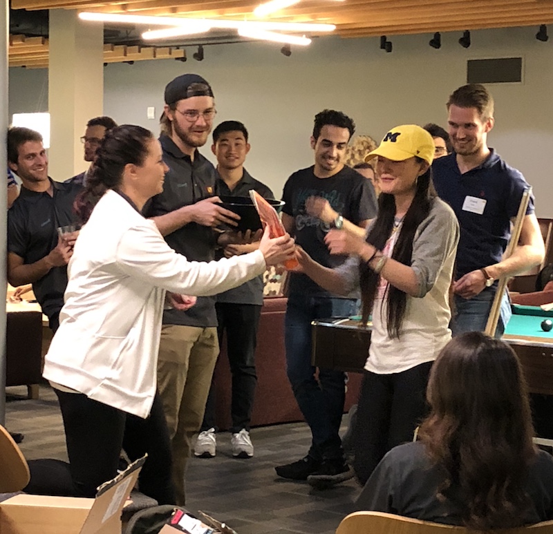 group of students standing around, one is handing an object to another