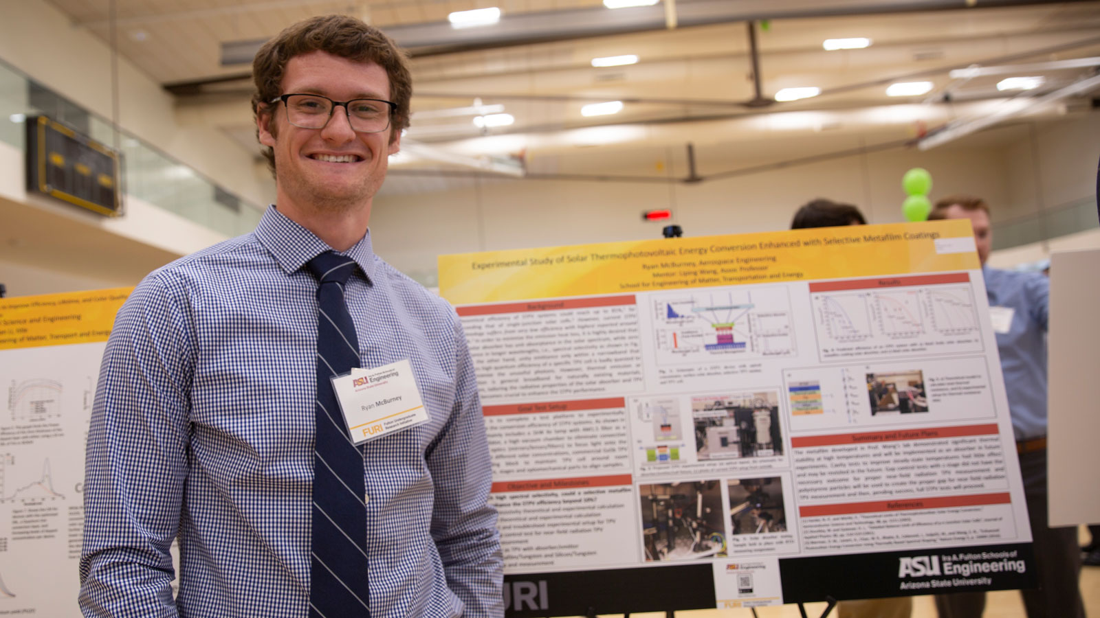 A student poses in front of a research poster.