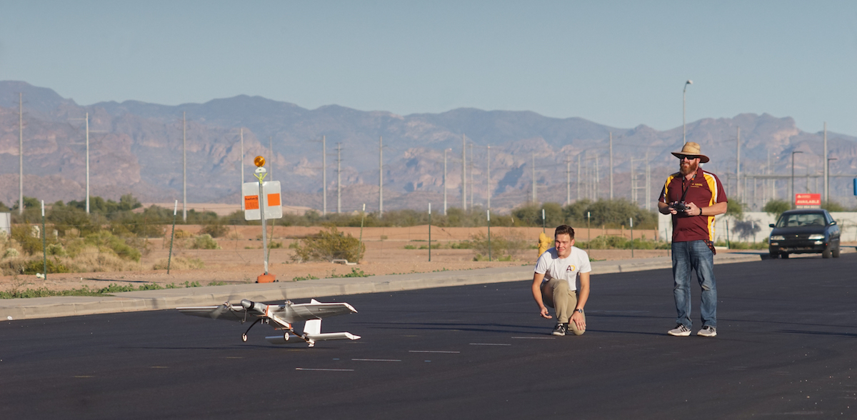 small airplane taking off with two students watching