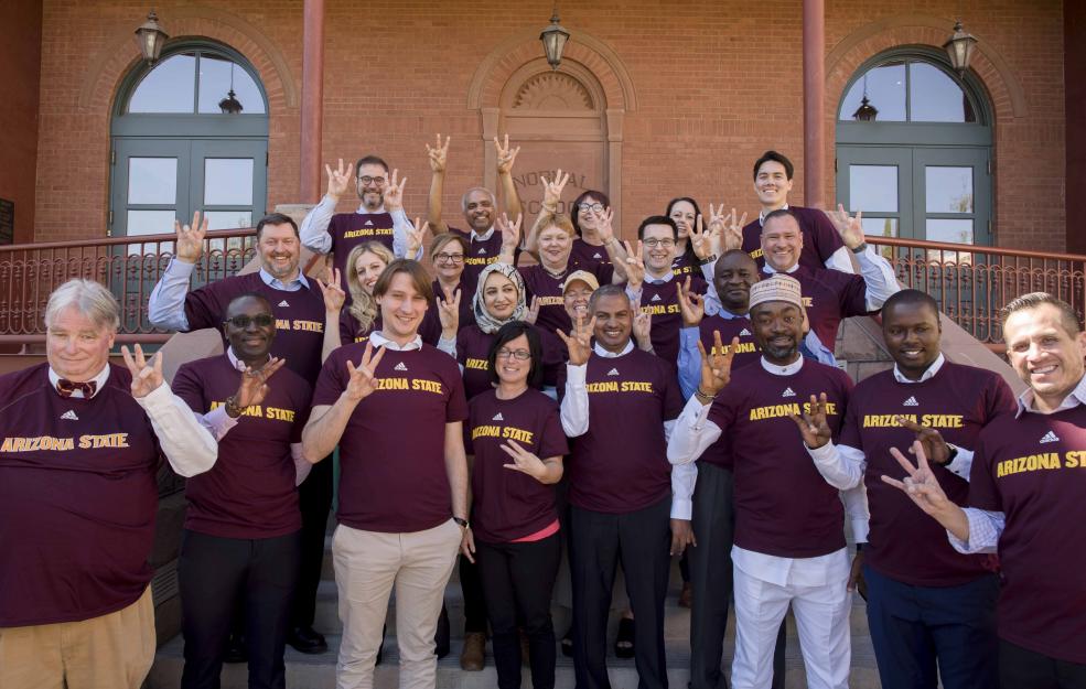 large group of people wearing matching ASU shirts making the "forks up" hand sign