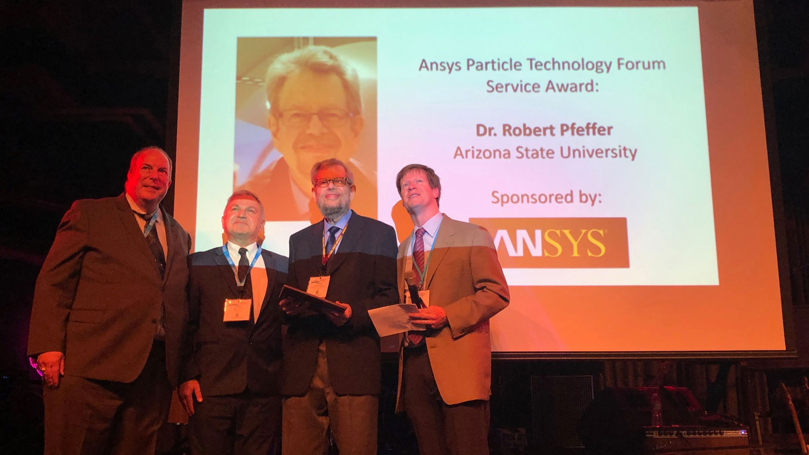 four men standing on a stage