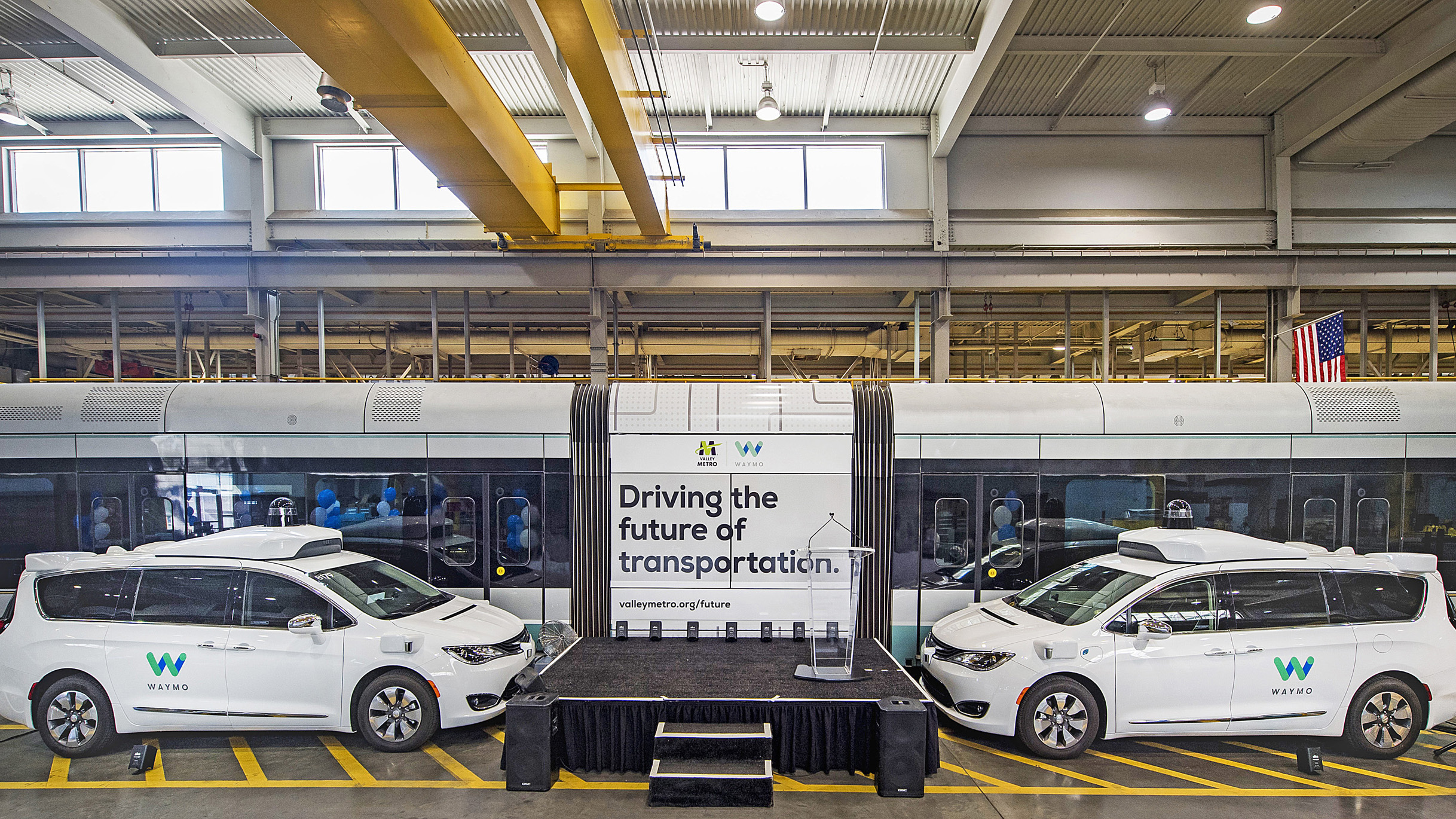 Pair of Waymo autonomous vehicles next to a stage