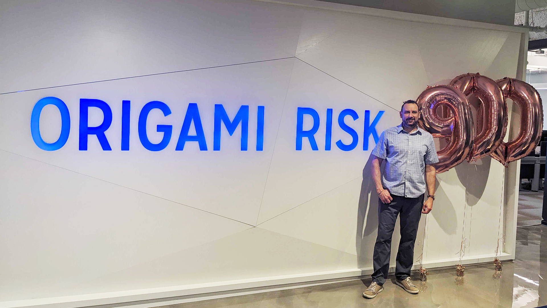 ASU alum Tim Cope stands in front of a sign for his software company, Origami Risk.
