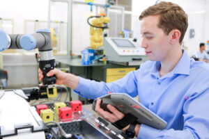 A student operates a robotic arm using a handheld control interface to sort colored blocks