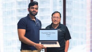 Two men standing on a stage and holding a laptop.