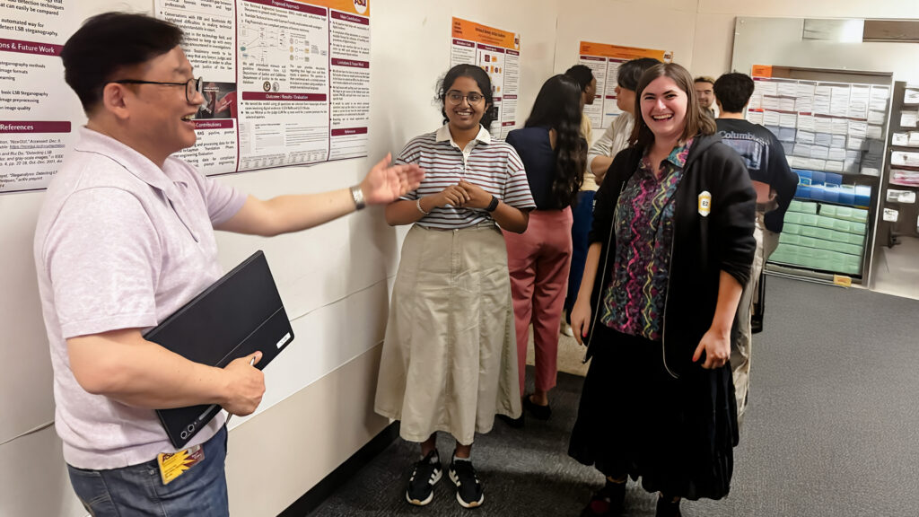 Gail-Joon Ahn speaks with students at a cyber forensics poster session.